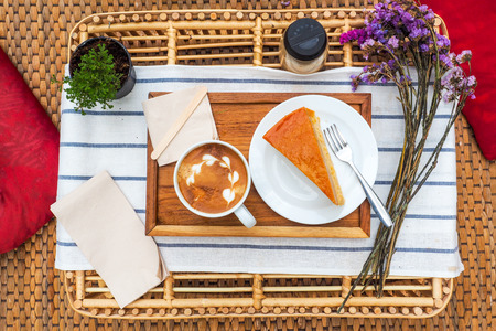 Coffee mugs on a wood tray with cake and flowers.の写真素材