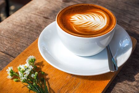 Coffee cup on a wooden table and a Little flower.の写真素材