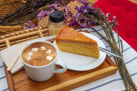 Coffee mugs on a wood tray with cake and flowers.の写真素材