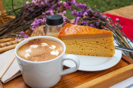 Coffee mugs on a wood tray with cake and flowers.の写真素材