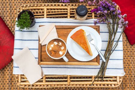 Coffee mugs on a wood tray with cake and flowers.の写真素材