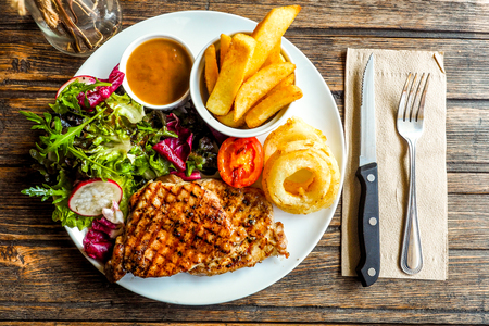 Grilled pork steak with vegetables salad and french friesの写真素材