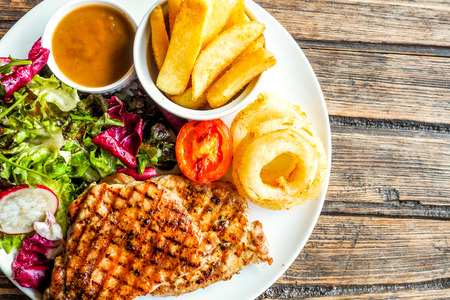 Grilled pork steak with vegetables salad and french friesの写真素材