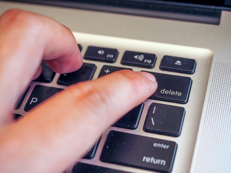 finger pushing delete button on a keyboard of computer