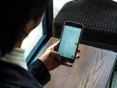 BANGKOK , THAILAND - April 18,2017: Businessman hold Smartphone with Google Maps application on Apple iPhone. Google Maps is a service that provides information about geographical regions and sites around the world.のeditorial素材