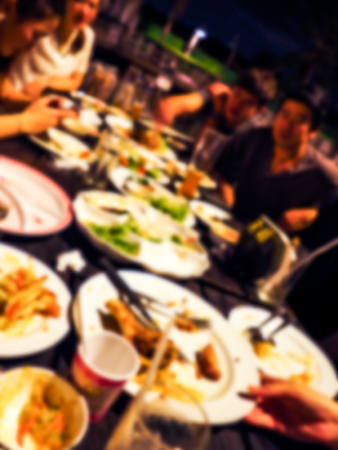 Blurred image of Friends holiday, sit and eat together. They are sitting at a wooden table with beers and thai food.の写真素材