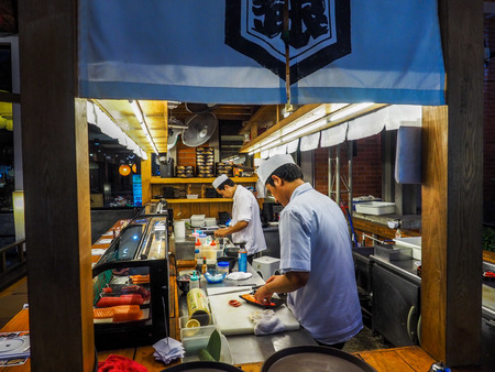 BANGKOK THAILAND - APRIL 25: Two young white chefs dressed in white uniform decorate ready dish in restaurant. They are working on maki rolls. Preparing traditional japanese sushi set in interior of modern professional kitchen in Asiatique The riverfront のeditorial素材