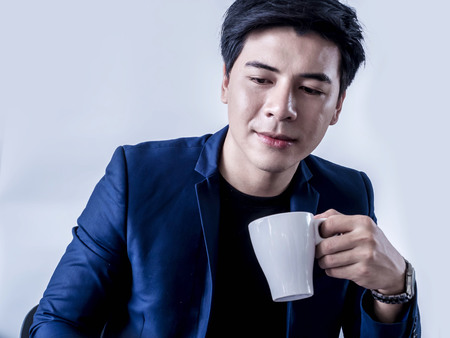 Young businessman drinking coffee thinking of a project in meeting room.の写真素材