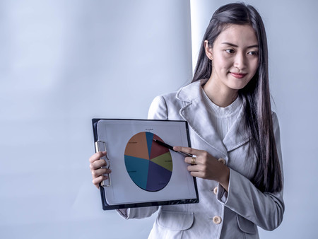 Portrait of beautiful intern standing at office in front of flip chart and presenting in the meeting...