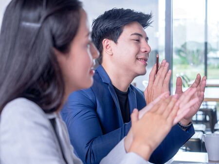 Business team applauding colleague at a meetingの写真素材