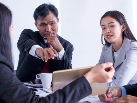 Satisfied senior businessman showing growing chart at his happy colleagues in officeの写真素材