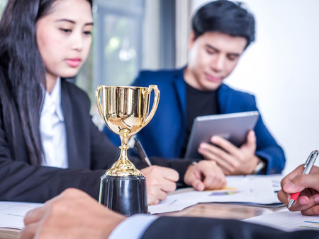 Businessman with teamwork in goal and successful trophy and rewarded for in the officeの写真素材