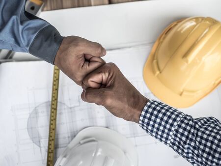 business, building, teamwork, gesture and people concept - group of smiling builders in hardhats...