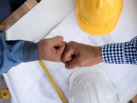 business, building, teamwork, gesture and people concept - group of smiling builders in hardhats greeting each other with Hand collision.の写真素材