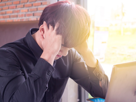 tired man with laptop and coffee having a work, businessman in office or homeの写真素材