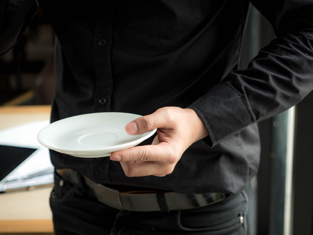 Man standing holding a coffee saucer.の写真素材