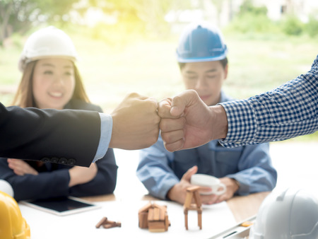 business, building, teamwork, gesture and people concept - group of smiling builders in hardhats greeting each other with Hand collision.の写真素材
