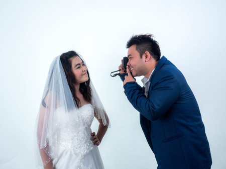 Wedding groom photographing bride with camera in studio.の写真素材