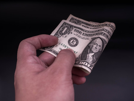 Hand handing over money in hand. US dollar (USD) bills. Concept of givingの写真素材