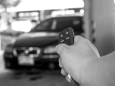 Man's hand open the car with car remote key at car park.の写真素材
