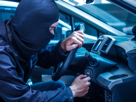 Car thief trying to start car with screwdriver in ignition. Car thief, car theft