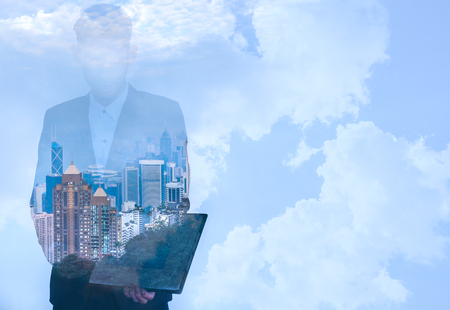 Business man using tablet with cityscape and sky backgroundの写真素材