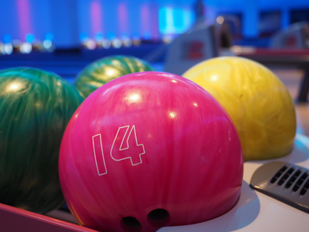 Bowling background. Interior of bowling alley lane with balls return machine closeup, selective focus on blue ballの写真素材