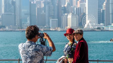 HONG KONG - DECEMBER 10,2016:Tourists take pictures and enjoy the famous Hong Kong island skyline across Victoria Harbour from the avenue of stars in Kowloon.のeditorial素材