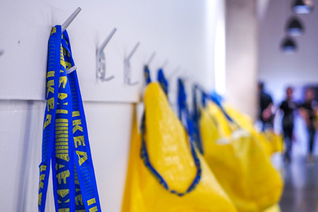 Big yellow shopping bags in the IKEA store hanging on the white walls.のeditorial素材
