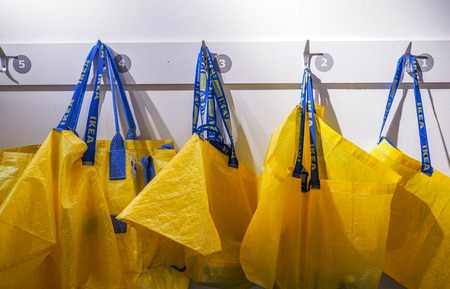 Big yellow shopping bags in the IKEA store hanging on the white walls.のeditorial素材