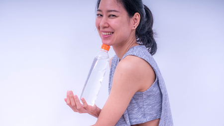 Happy young asian woman holding a bottle of water, Isolated on white background. Health Conceptsの写真素材
