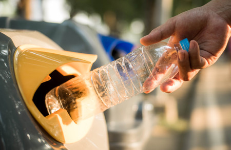 Hand throwing plastic bottle in recycling bin, global warmingの写真素材
