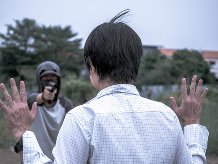 Robber holding a gun need some valuables from a businessman, Dangerous criminal in the cityの写真素材