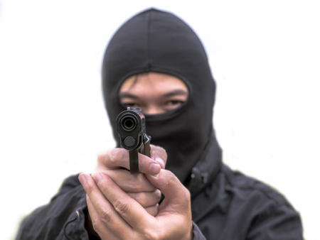 Man with the gun in dark clothes, robber in black hood holding gun and pointing to victim, Robbery crime.の写真素材