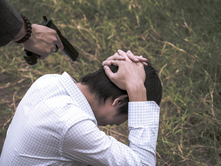 Portrait of Killer hand holding gun and put gun to businessman head.の写真素材