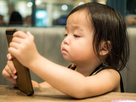 Little kid is playing with mobile phoneの写真素材
