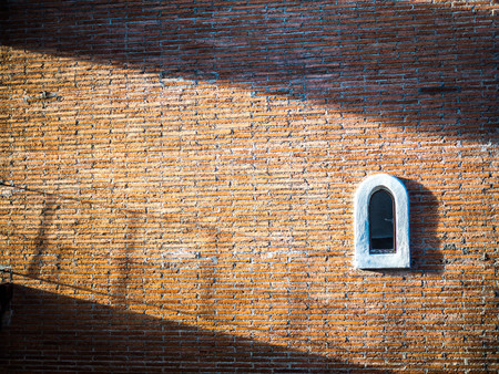 The brick wall has a small window on the right.