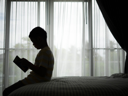 Silhouette of a Boy reading book in the bedroom