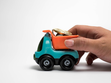 Hand hold toy car truck and money coins isolated on white background, bitcoinの写真素材