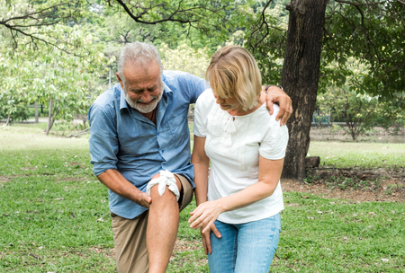 Old man with knee pain and women take care of him. Get first aidの写真素材