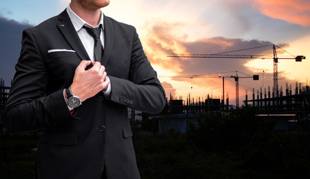 Confident young businessman looking away while standing outdoors with cityscape in the backgroundの写真素材