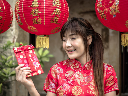 Asian woman on a costume festival holding a red pocket - lucky money. Tet holiday. Chinese New Yearの写真素材