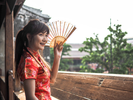 Portrait beautiful asian woman smile wear traditional chinese dress holding a fan.の写真素材