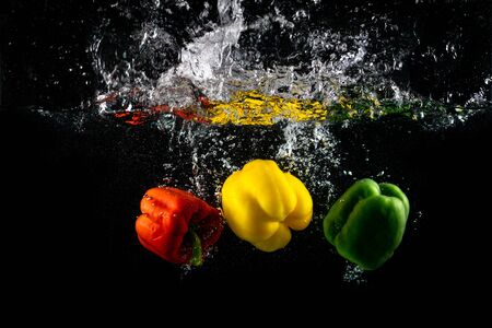 Three Paprika splash in water on black background, Capsicum annuum: bell pepper and buble.の写真素材