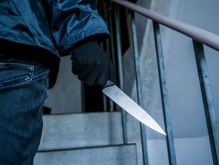 Man holding a knife in his hand are walking up the stairs, Threat Concept.