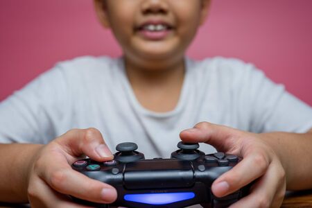 Bangkok, Thailand - September 12, 2019: Hand boy playing Sony Dualshock 4 controller for PlayStation 4 pro, video game-addicted children.のeditorial素材