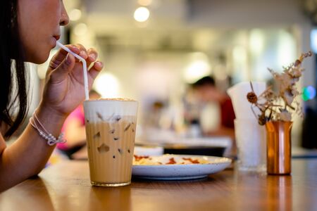 Beautiful young woman enjoying latte coffee in cafe, Woman sucks ice coffee with milk.の写真素材