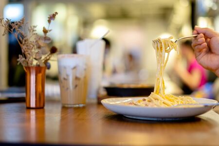 Spaghetti Carbonara in the dish on the wooden table in a restaurant. Italian food.