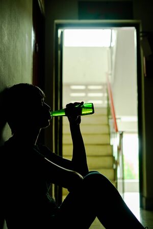 Silhouette of drunken man drinking beer are having stress in life and unable to find a solution and no advisor, from work problems And a failed family life. copy space background for text.の写真素材