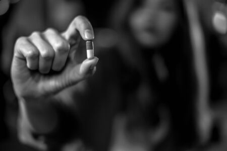 Close up of woman taking in pill, Medicine, Drugs, A capsule held between two fingers, health care...